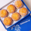 Open Borough 22 box of six gluten free oat free vegan fried sugared doughnuts filled with lemon curd, the filling visible at the side of each one