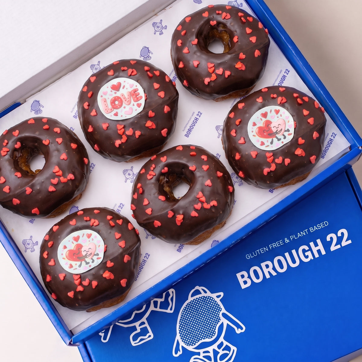 Gluten free vegan doughnuts with chocolate icing, red heart sprinkles and Love toppers in a Borough 22 box